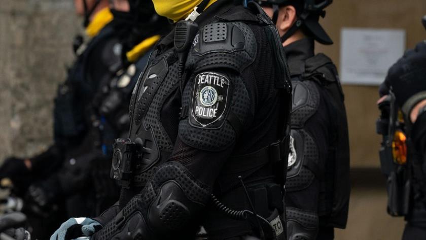 Iranpress: A US police officer riding his bicycle over a protester